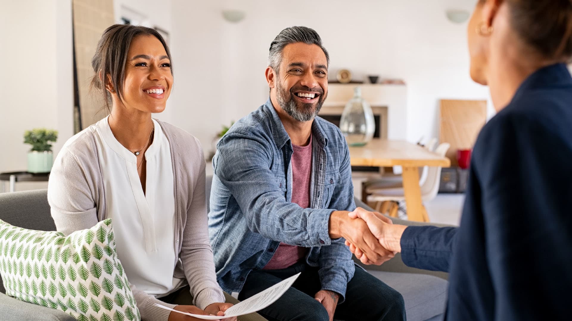 A couple shaking hands with a mortgage broker.