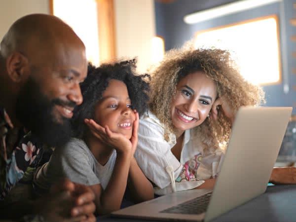 Father, mother and young girl looking at a laptop and smiling