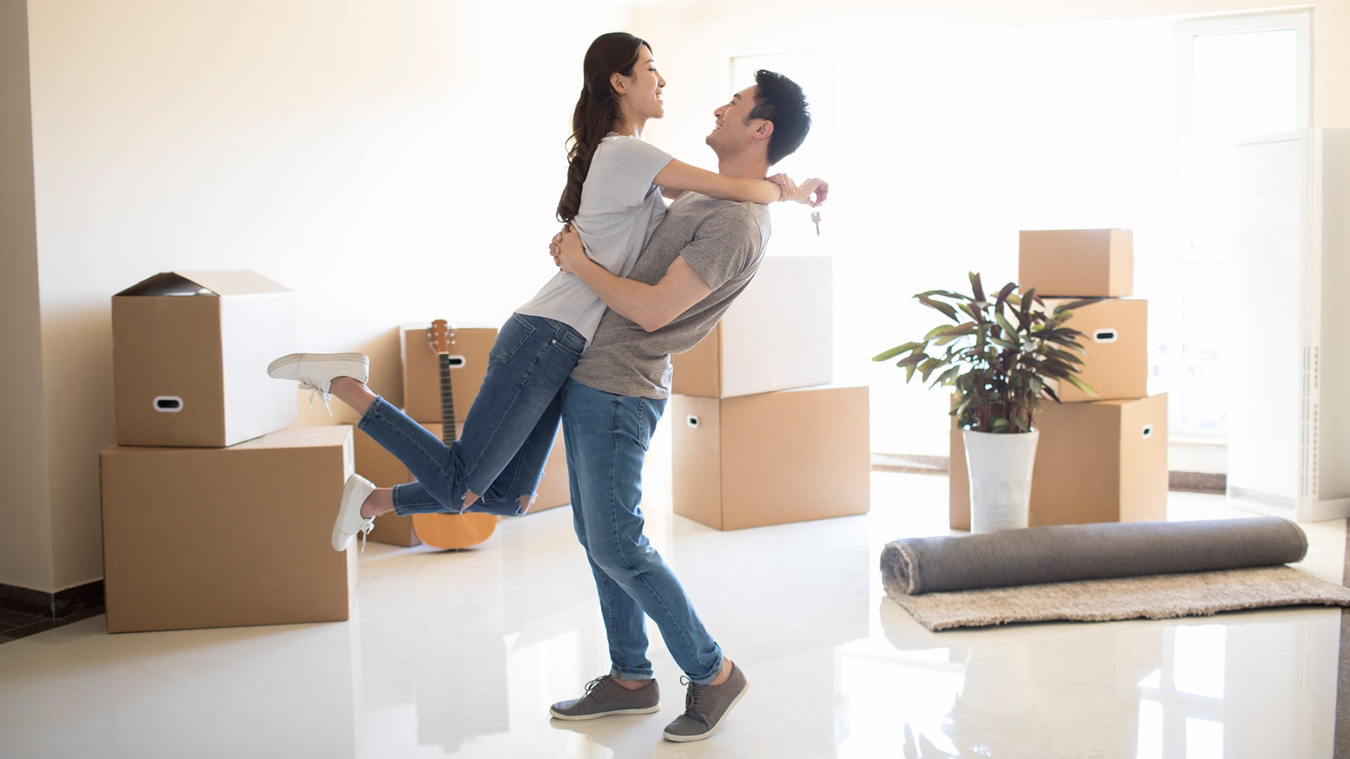 young woman jumping into her husbands arms in new house