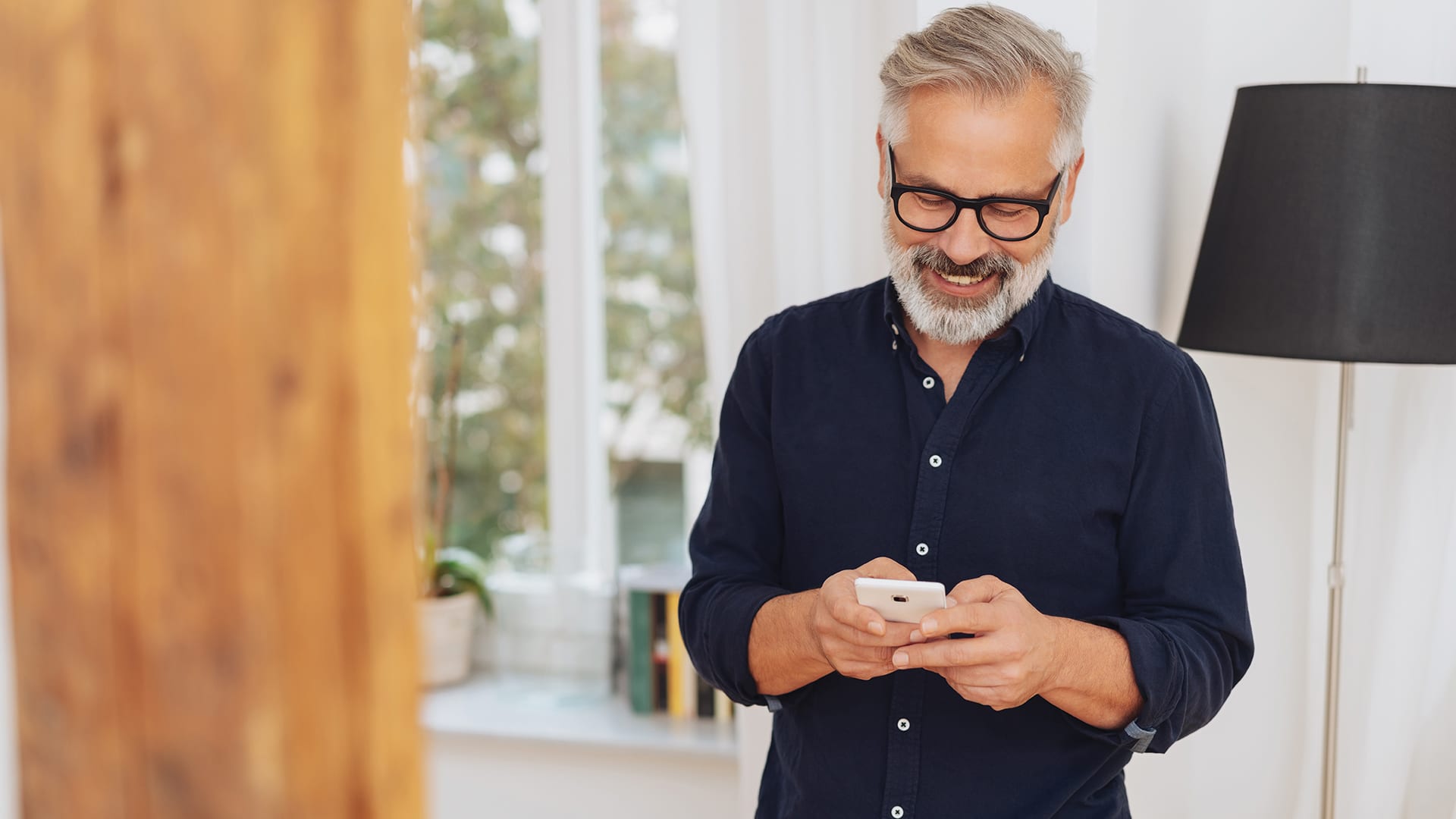 middle aged man smiles while using his smart phone